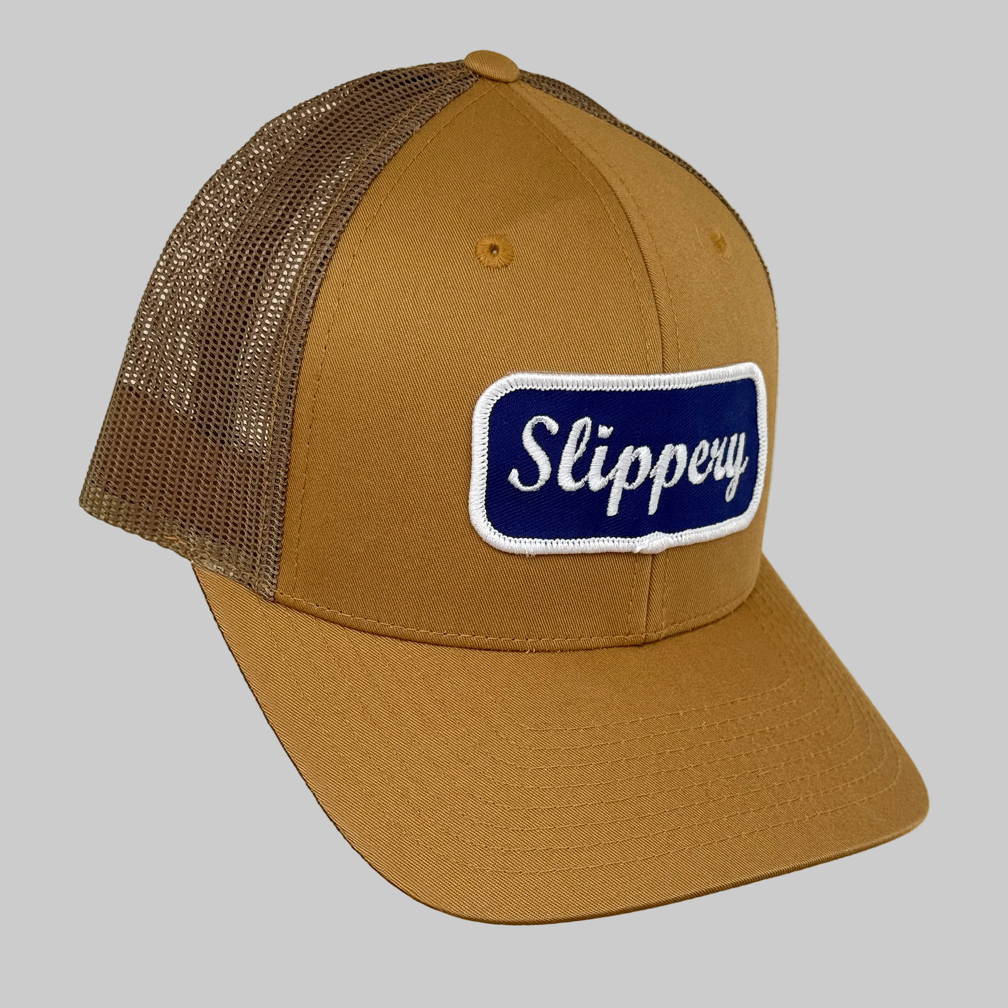 Brown trucker cap with mesh back and 'Slippery' logo on a beige background