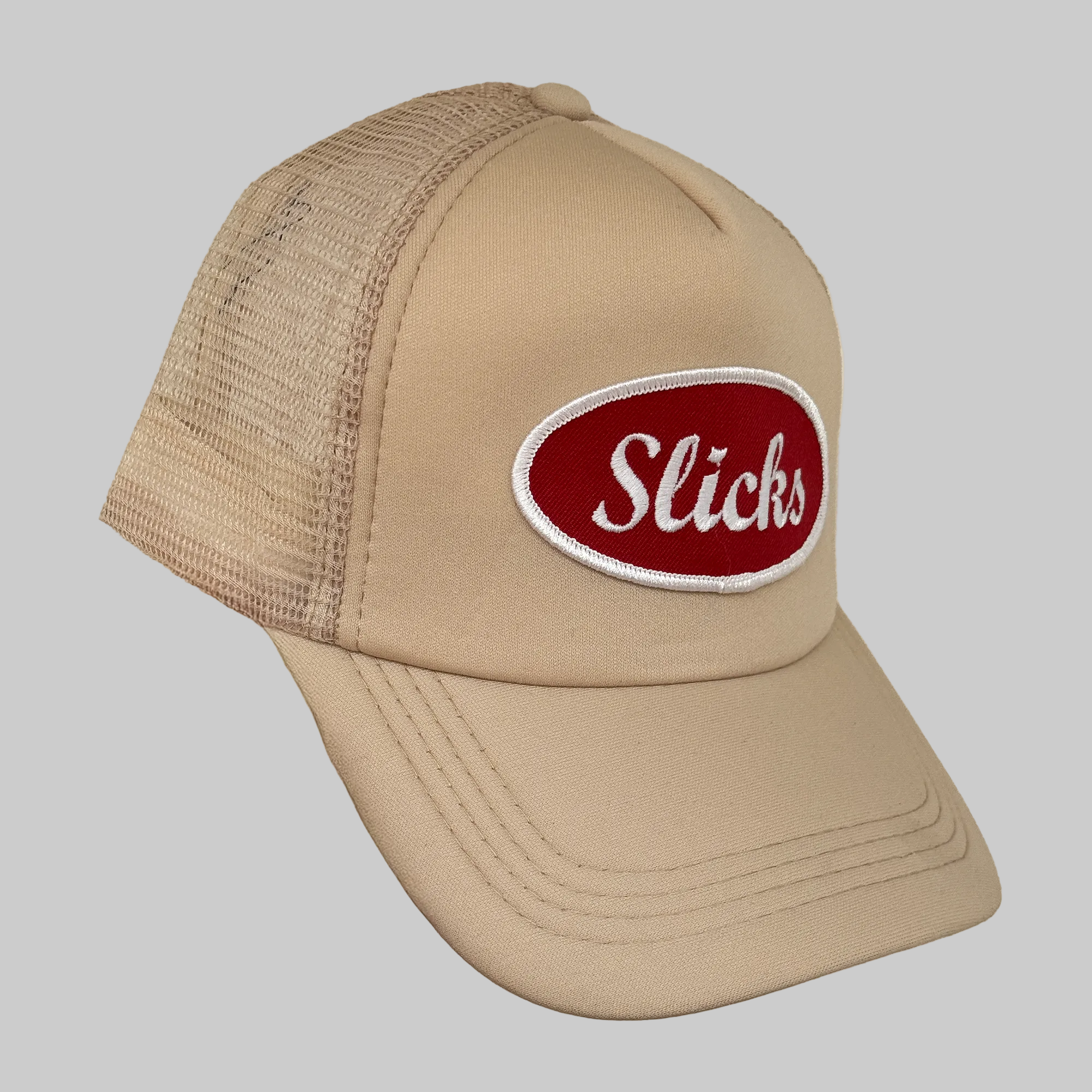 Beige trucker cap with a red and white 'Slicks' logo on a beige background